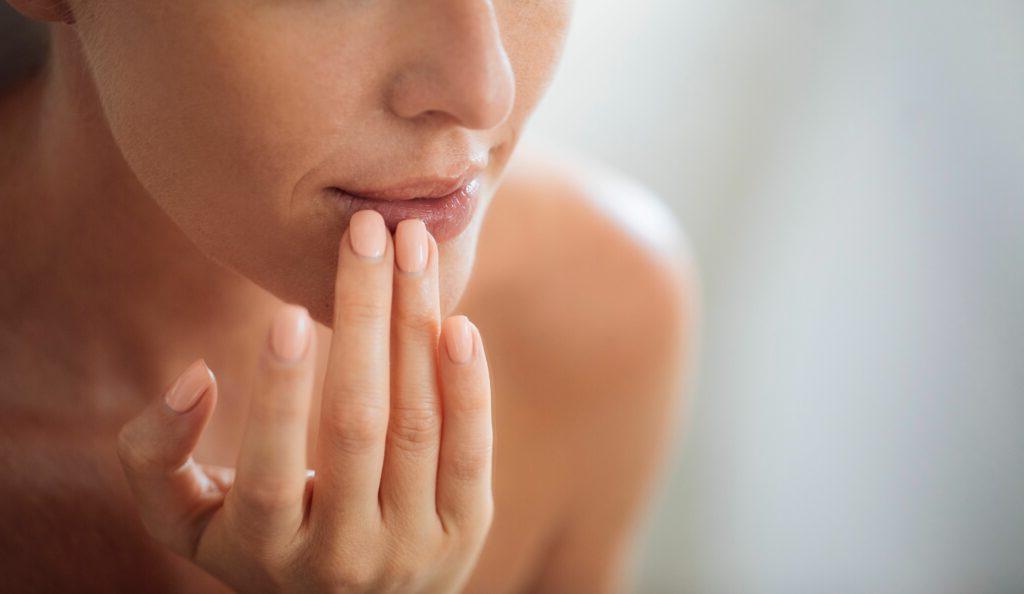 Patient performing lip injection aftercare 